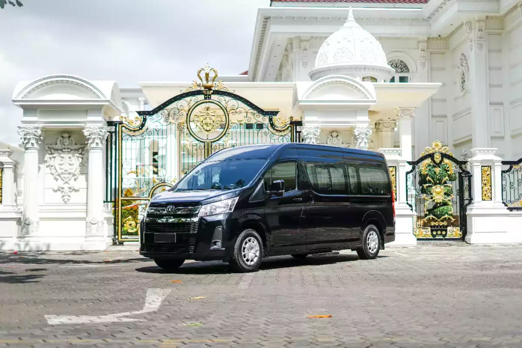Dark Toyota HiAce van waiting at a Balinese gate