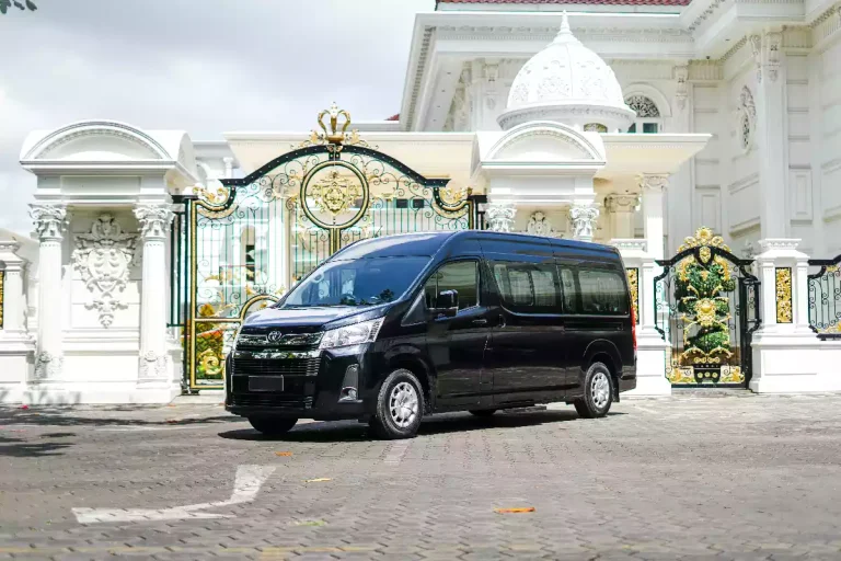 Dark Toyota HiAce van waiting at a Balinese gate